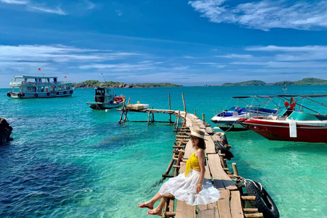 une fille assise à un ponton de mer avec des bateaux à phu quoc au Vietnam