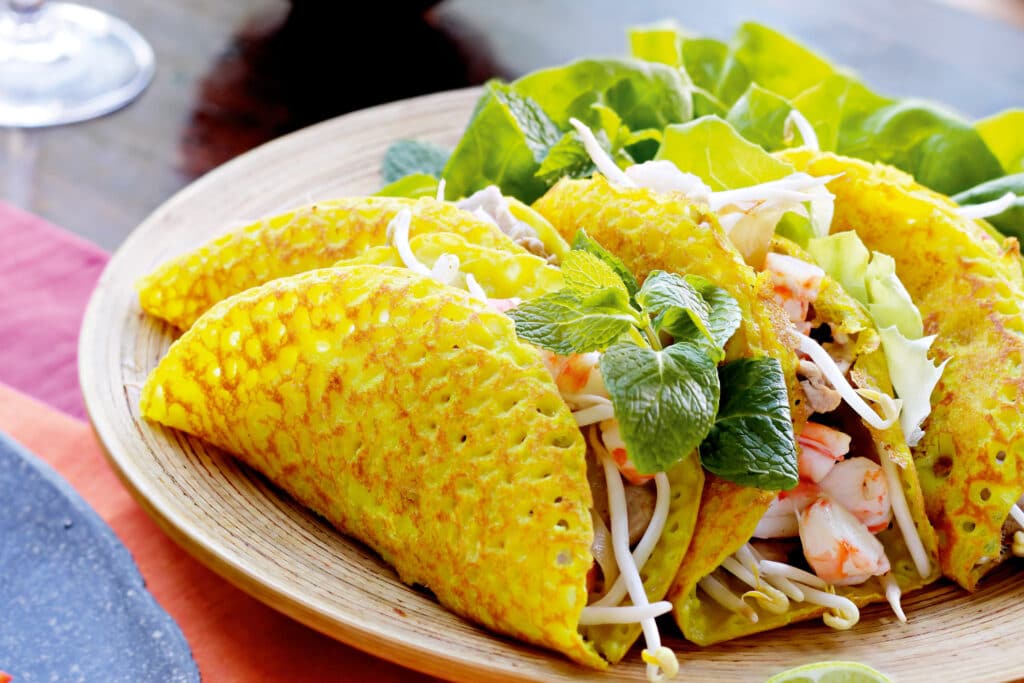 Une crêpe dorée bánh xèo garnie de légumes et de crevettes.