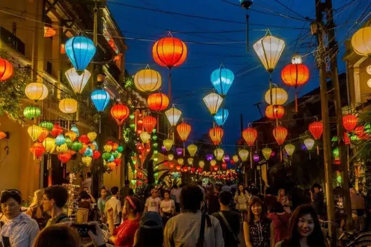 Rues illuminées par des lanternes à Hoi An avec des reflets colorés sur la rivière.